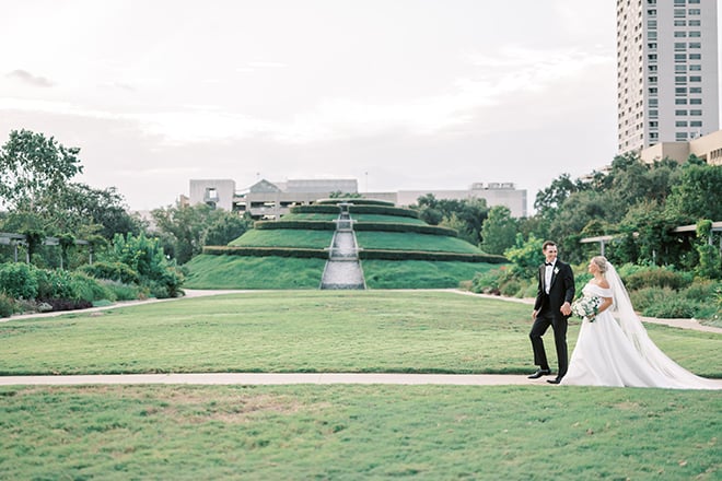The bride and groom hold hands as they walk through McGovern Centennial Park.