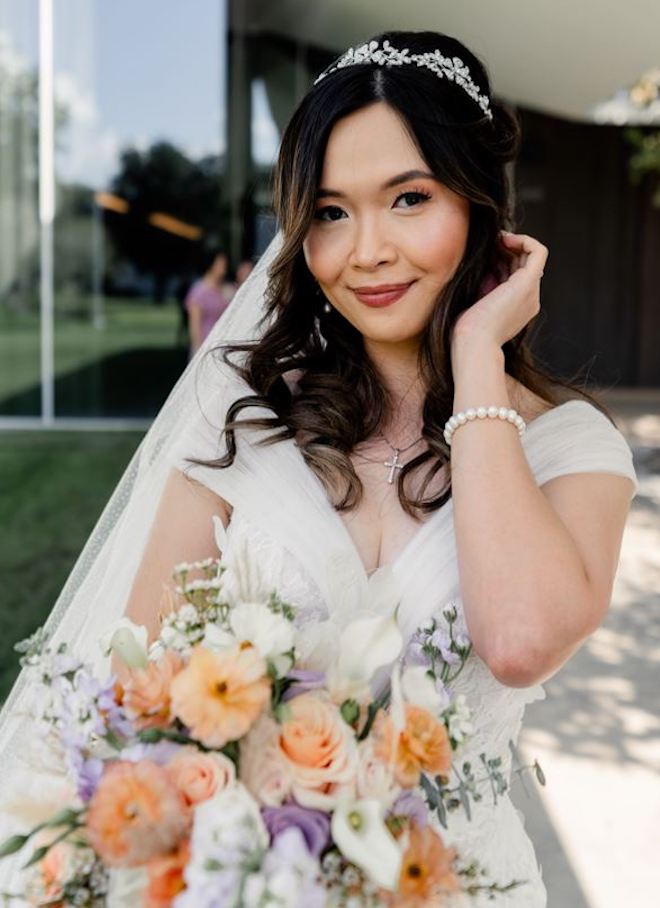 Bride holding bouquet with her hand behind her ear for her wedding day.