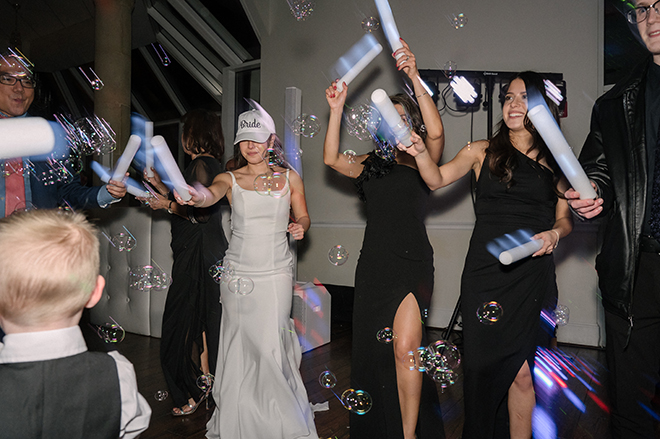 The bride dances on the dance floor with bubbles and light up sticks with wedding guests.