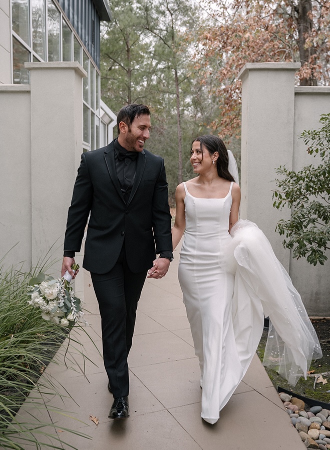 Mandi Roach Photography captures photos of the bride and groom holding hands walking outside their wedding venue. 