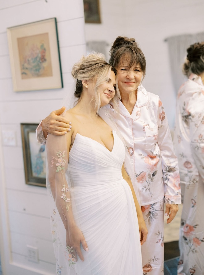 The bride resting her head on her mother's shoulder while getting ready. 