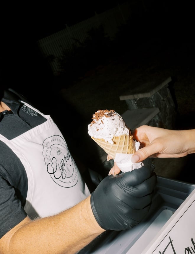 An ice cream cone being handed to a guest. 
