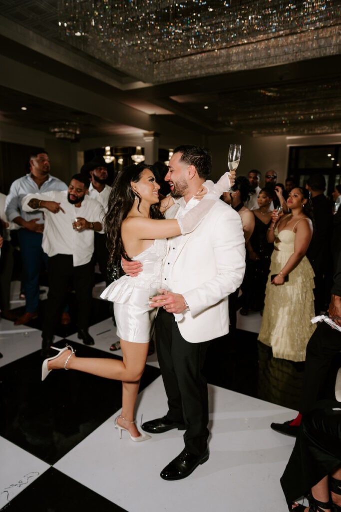 The bride hugging the groom on the dance floor while wearing her customized mini dress from her mom's wedding gown.
