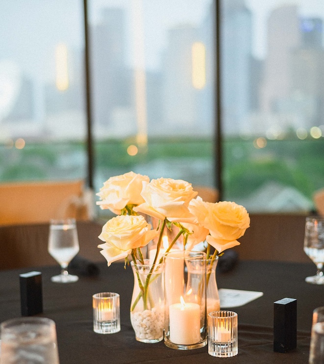 White roses in bud vases on the tables of the reception. 