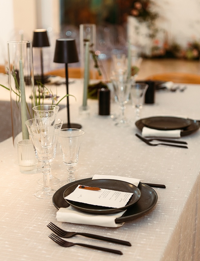 Black flatware is placed on the reception tables for the art gallery wedding. 