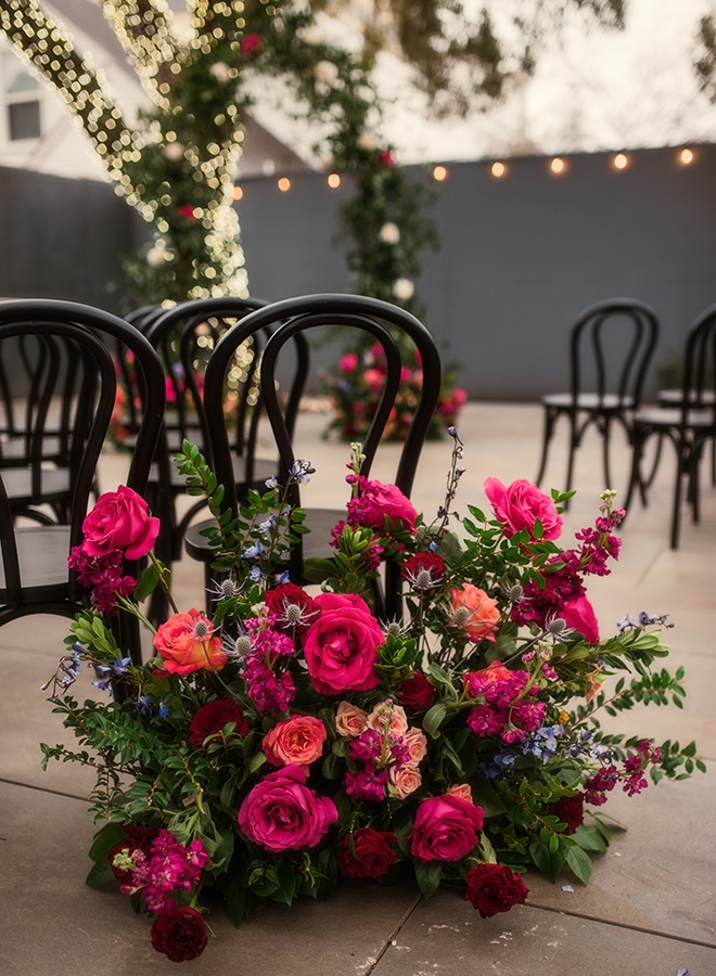 Dark floral arrangements line the aisle  at the outdoor wedding ceremony. 