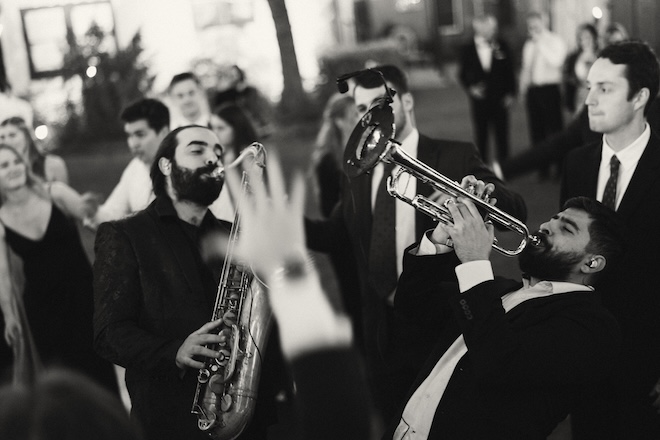 Hybrid 7 Band members play the trumpet and saxophone on the dance floor at the outdoor wedding reception. 