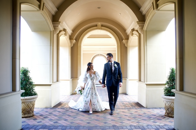 A bride and groom holding hands under the arches of Royal Oaks Country Club in west Houston. 