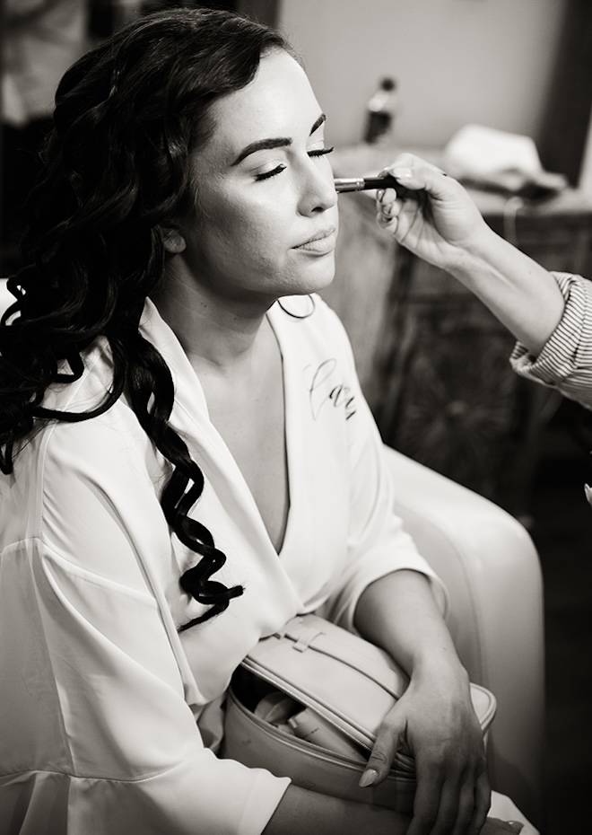 The bride gets her make up done of her wedding day. 