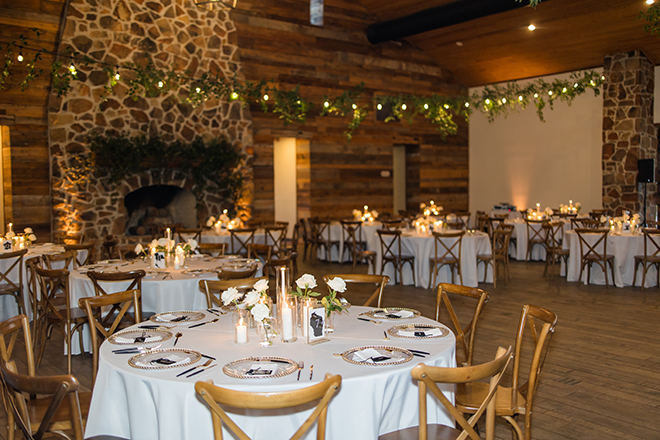 White roses in bud vases and taper candles decorate the reception tables. 