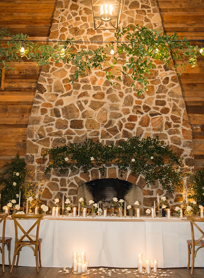 White roses in bud vases and taper candles decorate the the couples emerald and gold wedding. 