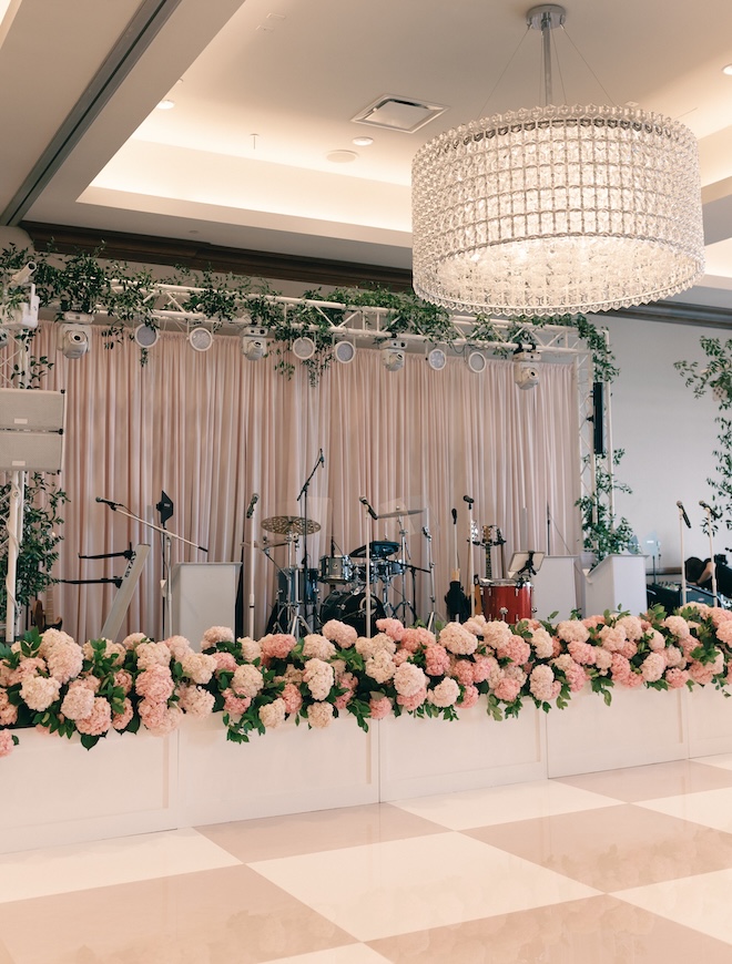 Pink hydrangeas decorate the stage in front of the pink and white checkered dance floor in the ballroom of Hotel Zaza. 