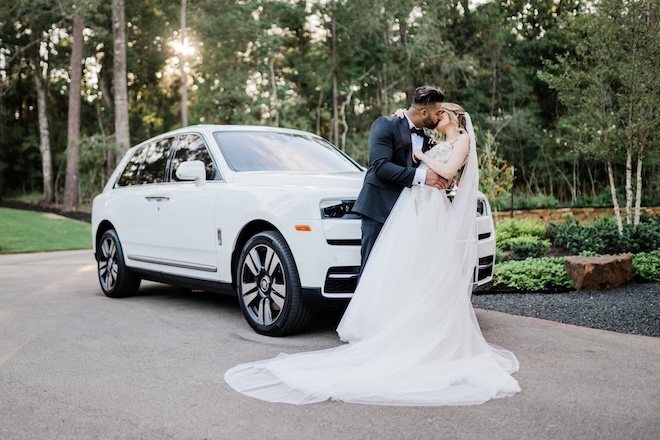 The couple kisses in front of a luxury white car from iExotic Car Rental & Chauffeur. 