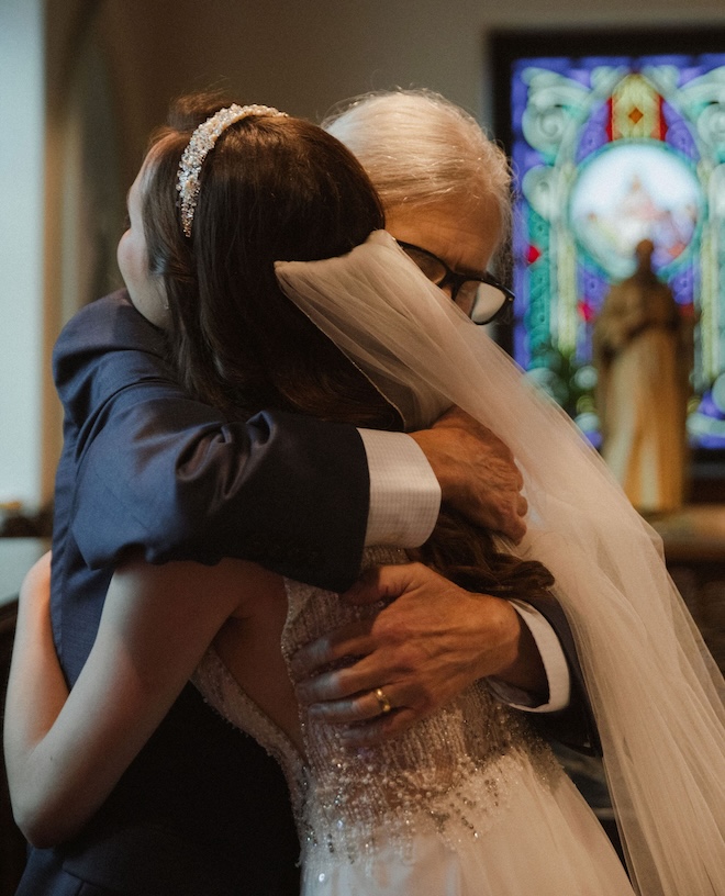 The bride and her father hugging at the church. 