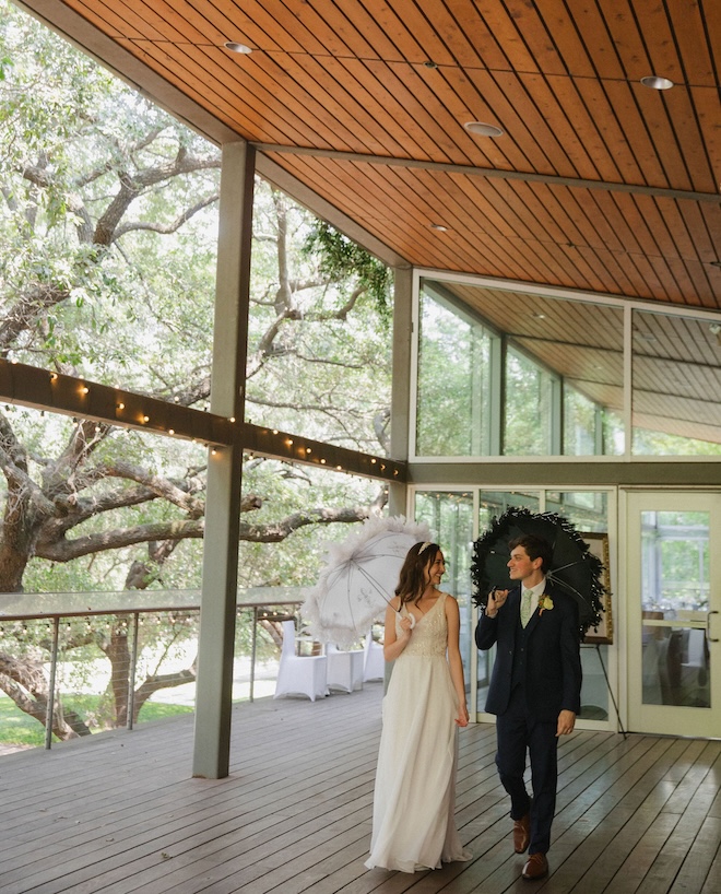 The bride and groom holding white and black feathered umbrellas leaving the Grove for their New-Orleans inspired second line dance. 