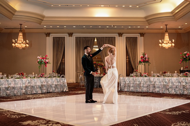 The groom spins the bride around on a white dance floor in the ballroom at Hilton Houston Post Oak. 