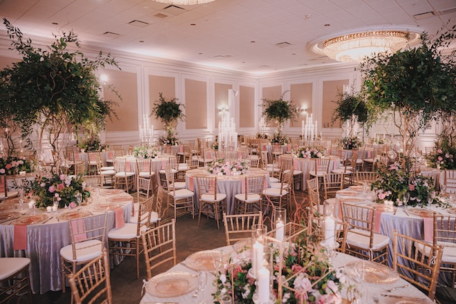 Greenery, pink decor and candles decorate the tables in the ballroom at The Westin Galleria Houston. 