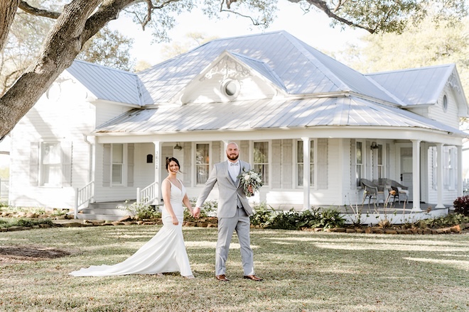The bride and groom hold hands in front of The Pattison House.