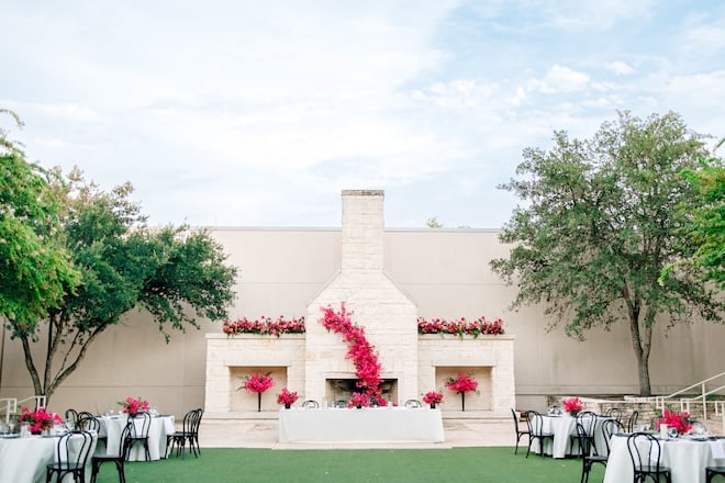 Pink florals decorate the limestone fireplace at the outdoor reception at Hyatt Regency Hill Country Resort & Spa. 