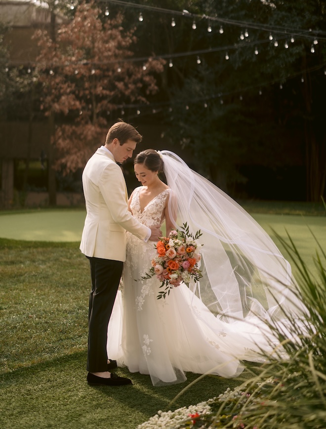 The bride and groom stand on the grass of The Houstonian Hotel, Club and Spa.