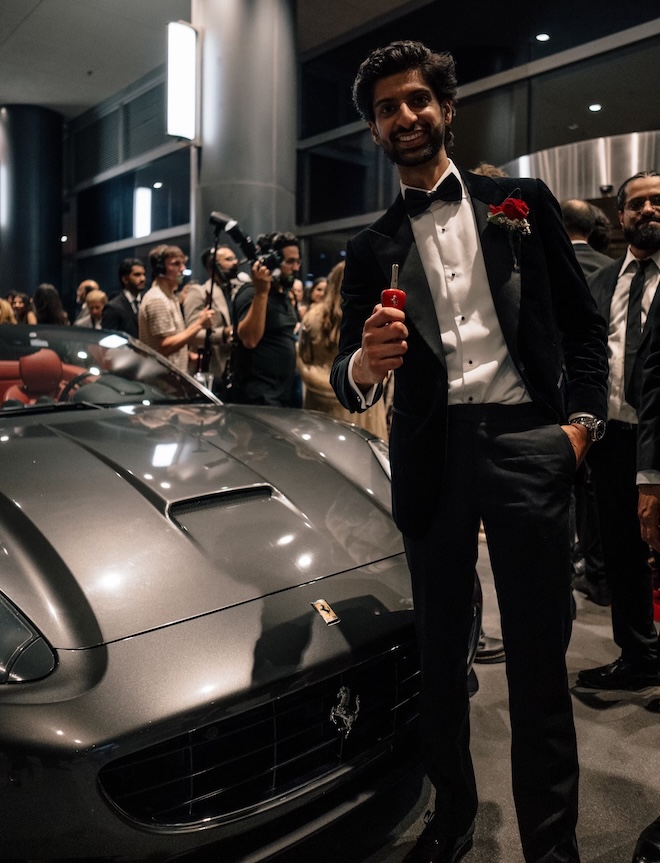 The groom smiles next to an exotic car outside of a Houston hotel.