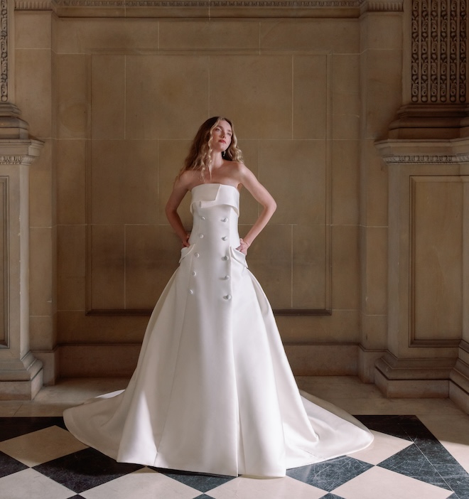 A bride wearing a strapless gown with buttons down the front and pockets. 