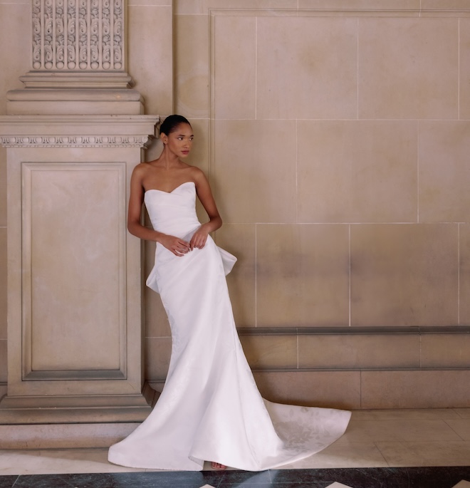 A bride wearing a strapless wedding gown with an over-sized bow in the back.