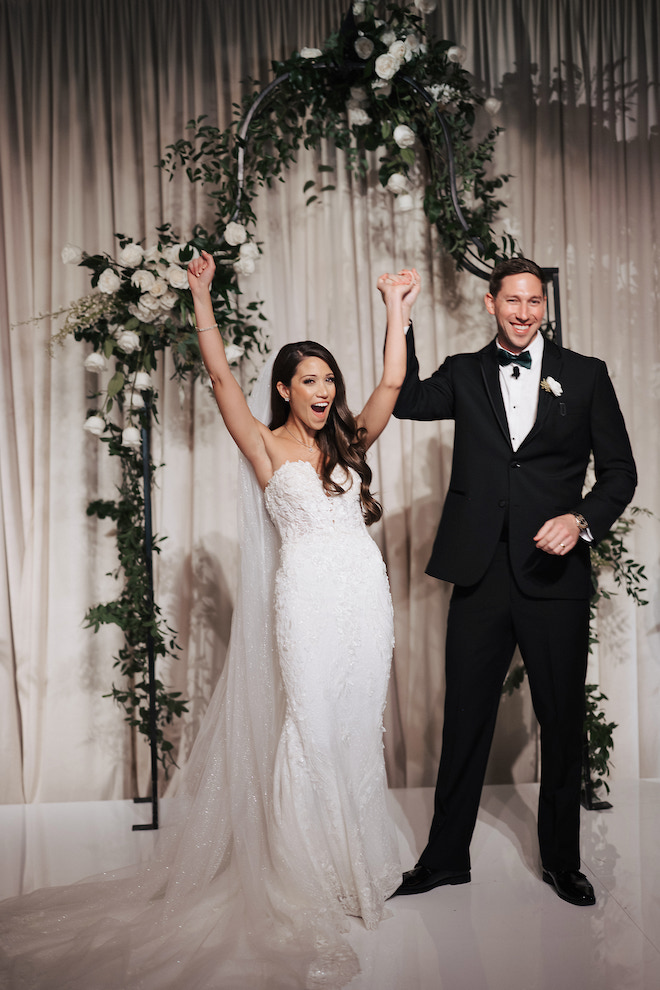 Bride and groom celebrating at altar with held hands in the air.
