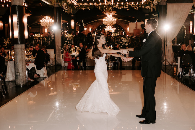 Bride and groom dancing on the dance floor while holding hands.