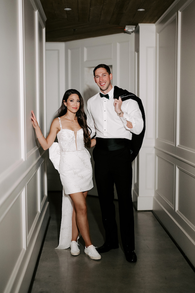 Bride and groom in venue hallway after bride changed into mini reception dress with a big bow on the back. 