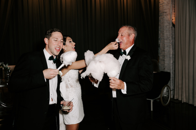 Bride feeding an elder of the wedding party cotton candy with the groom right next to her.
