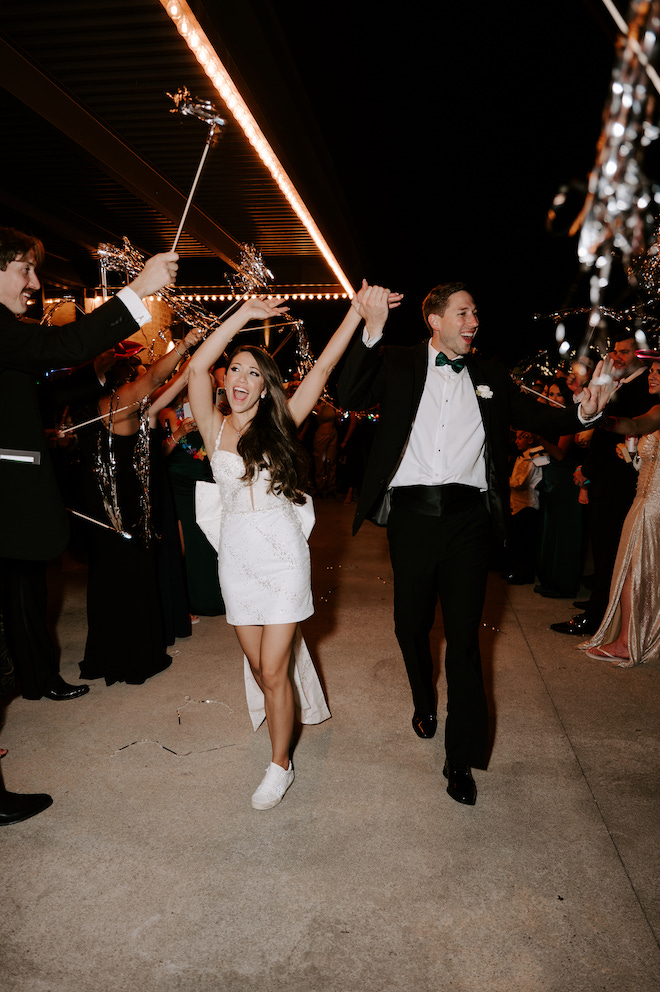 Bride and groom exiting with guests surrounding them cheering with streamers.