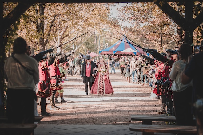 The bride walking down the aisle under swords.