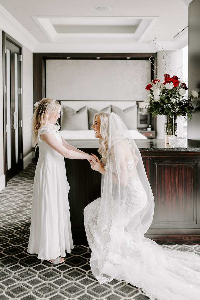 The bride kneeling in front of groom's daughter in hotel room to do vows with her.