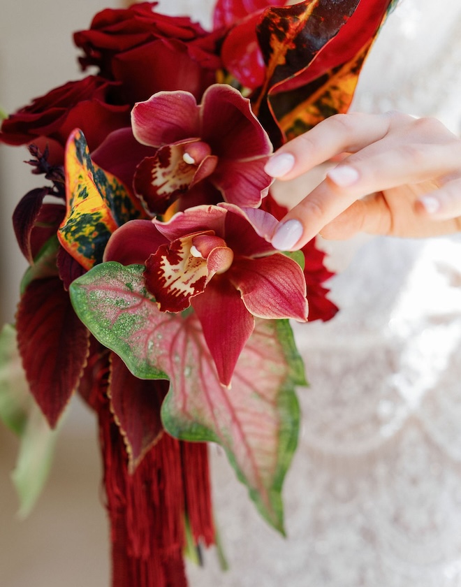 Bride holding a red floral bouquet. 
