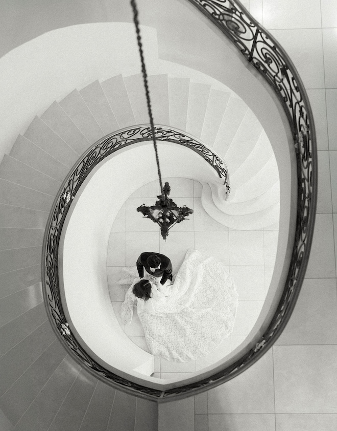 The couple posing below a spiral staircase. 