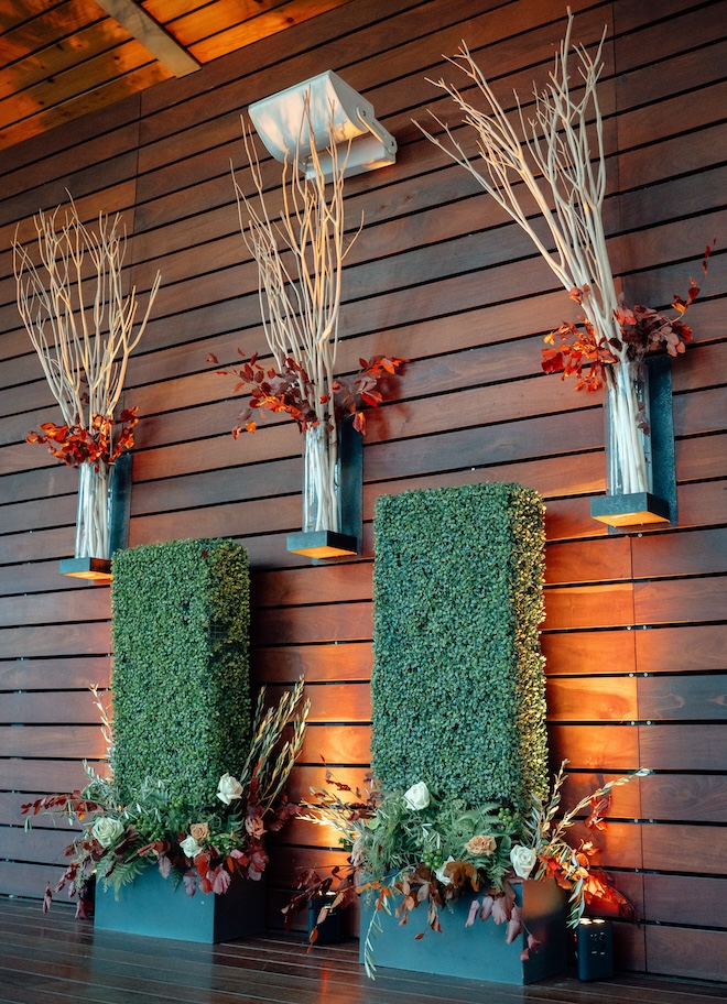 Autumn-hued floral arrangements and wooden sticks on a wooden wall at The Grove.