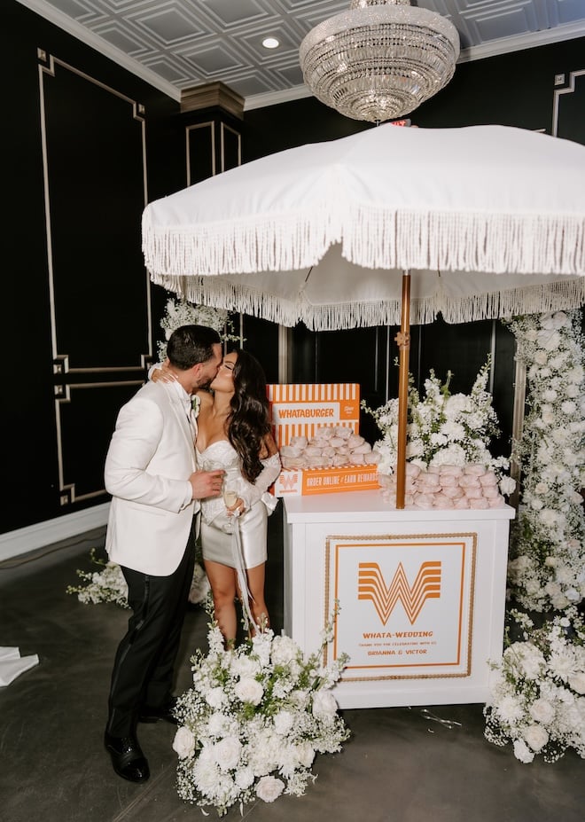 The bride and groom share a kiss next to honey butter chicken biscuits from Whataburger for their late night wedding snack. 