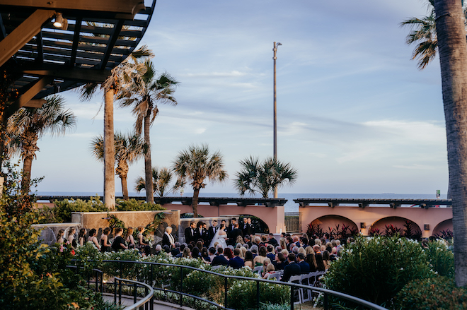 Far view of couple at the altar outside of the venue with an ocean view of the back.