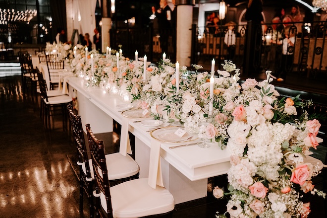 A floral runner with white and pink flowers runs down the middle of the reception table at The Astorian. 