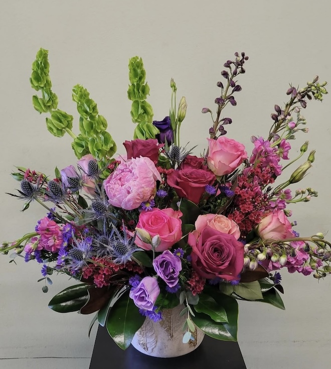 A floral arrangement with pink and purple flowers by Lush Flowers. 