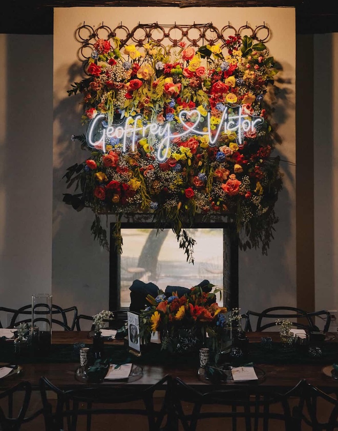 A floral installation with vibrant florals hangs above the reception table. 