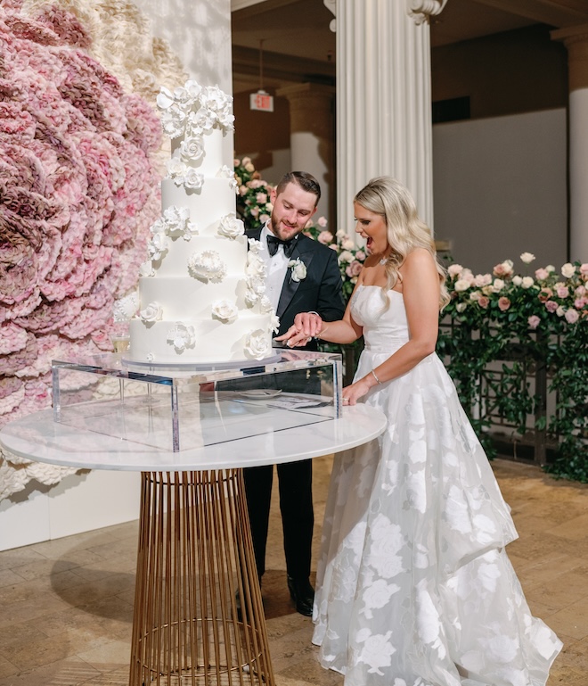 The bride and groom cut into their wedding cake. 