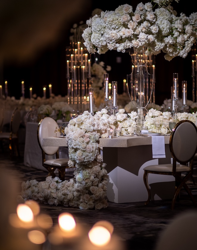 A dark ballroom with moody lighting, candlelight and white florals. 