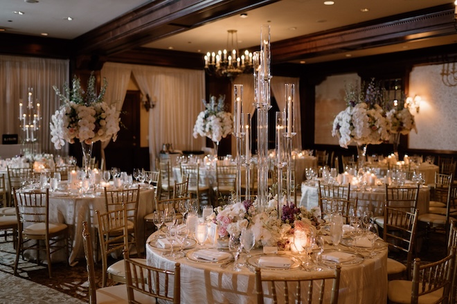 Round reception tables decorated with florals and candlelight creating a moody ambiance. 