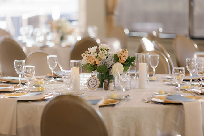 Pastel flowers, candle and hand embroidered table numbers decorate the reception tables. 