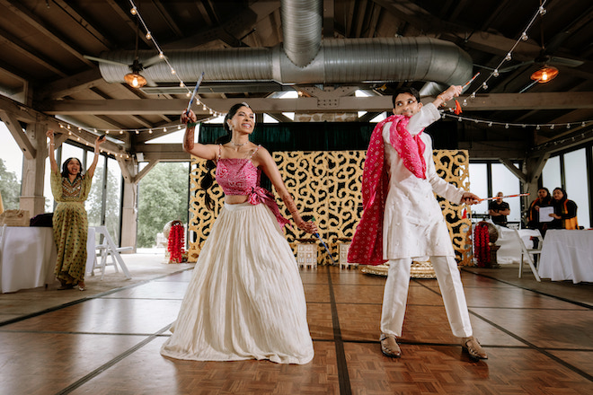 Bride and groom in thier pink haldi attire dancing before the ceremony.