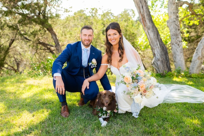 The bride and groom smile next to their dog in the Texas Hill Country.