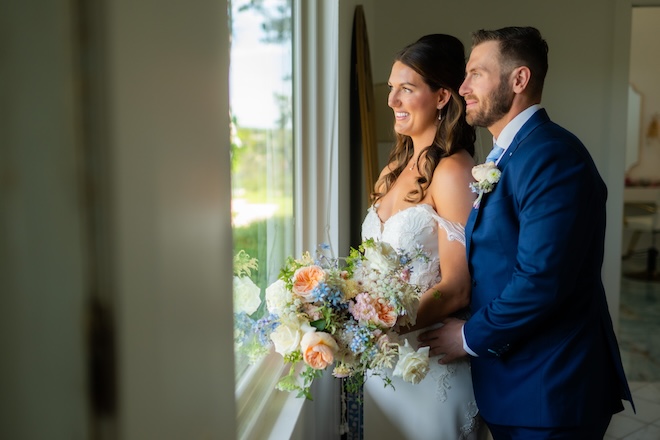 The couple looks out the window of their wedding venue.