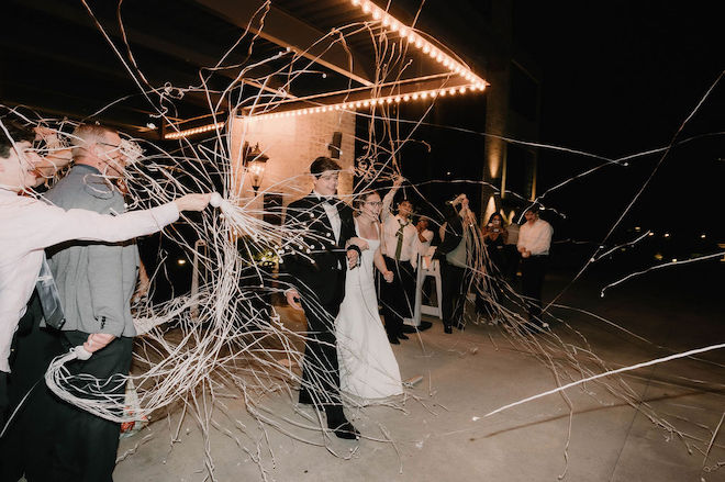 Bride and groom making their exit with guests holding streamers for them.